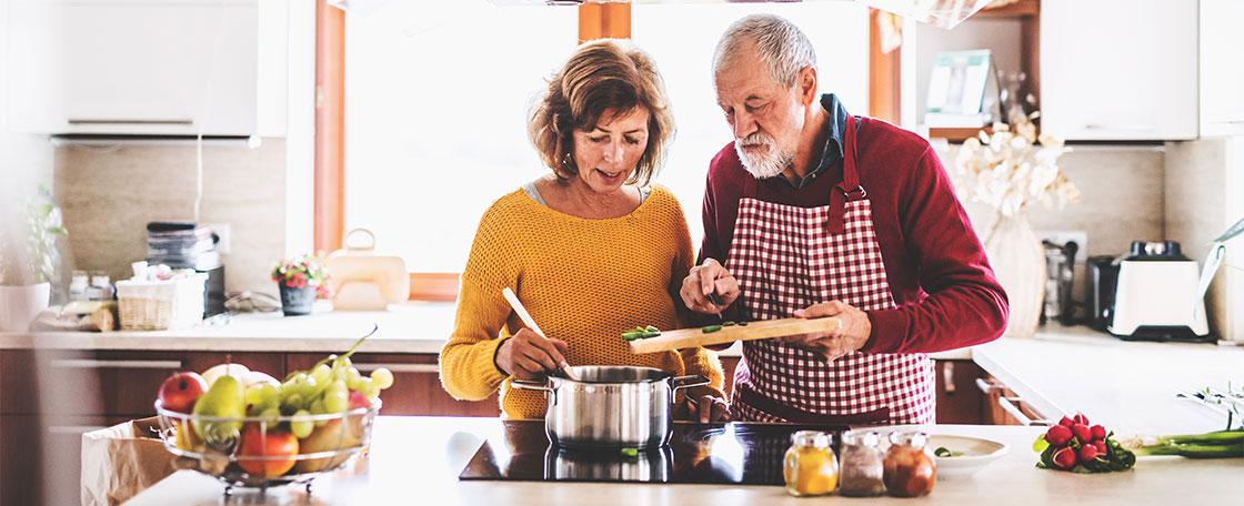 An older couple cooking. 
